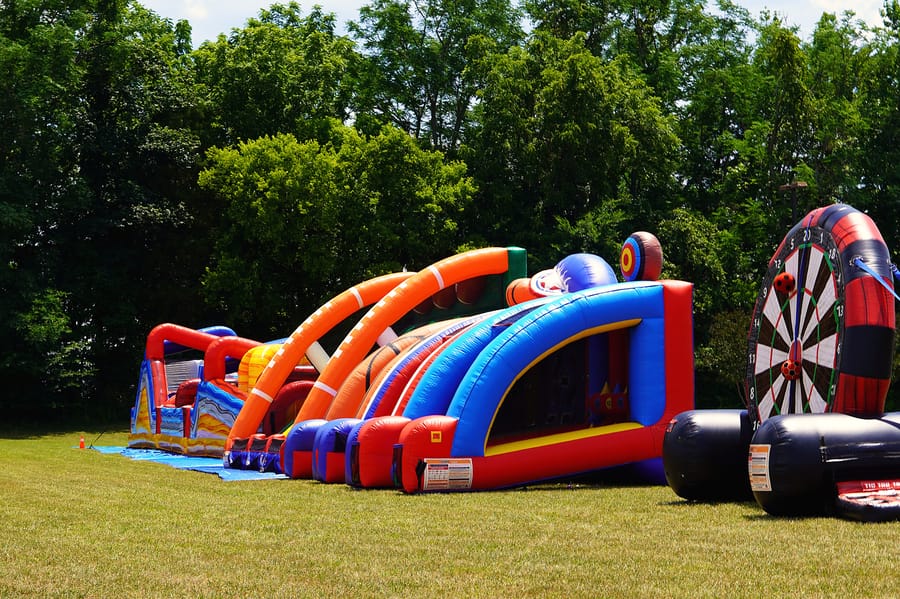 Inflatable slides and an obstacle course set up on the grass for the kids