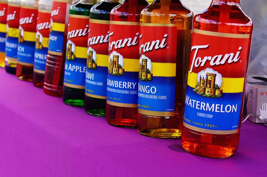 A colorful row of snow-cone syrups lined up on a vendor table