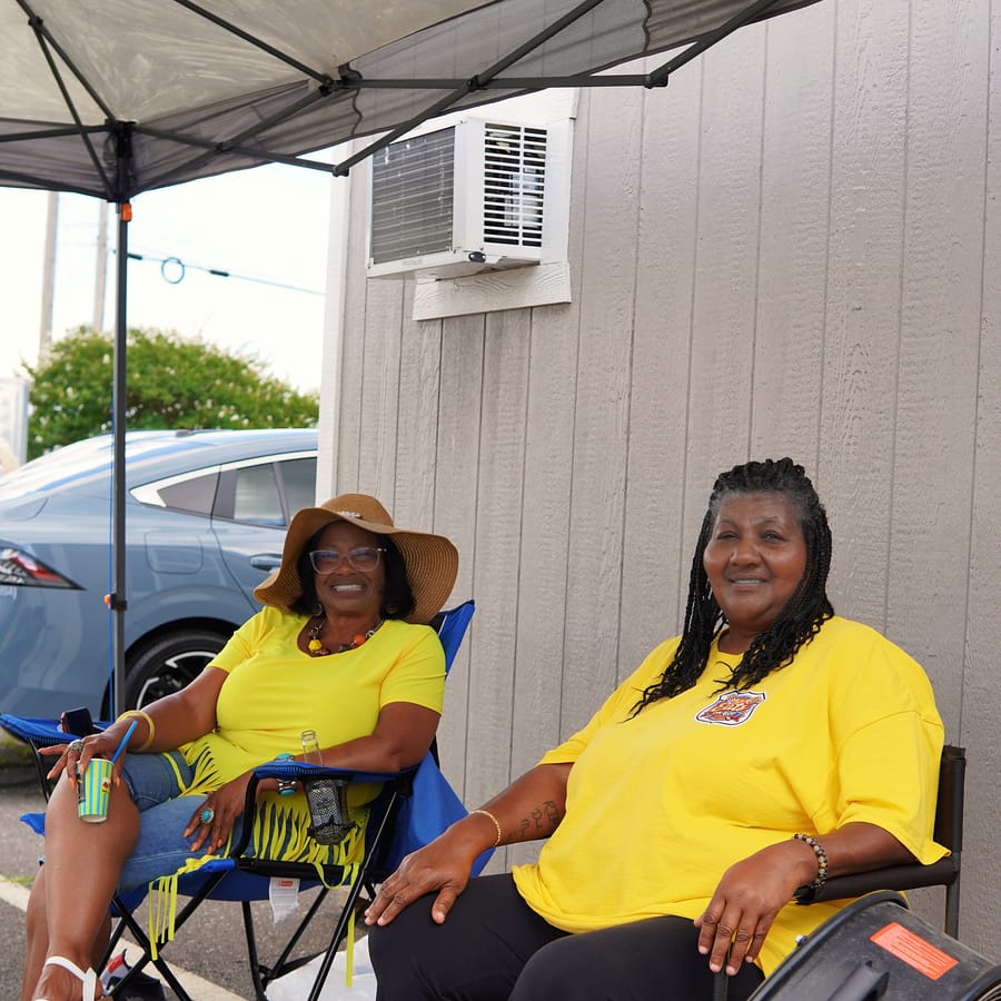 Two Eats on 601 organizers in matching yellow shirts, smiling under the tent at the Summer Kickoff
